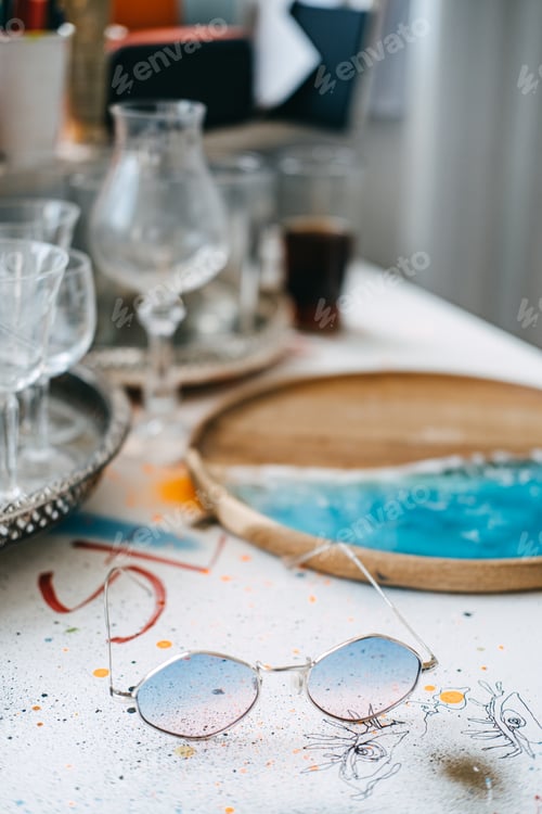 Preview: Retro round sunglasses on a colorful art-stained table, creative workspace, bohemian lifestyle
