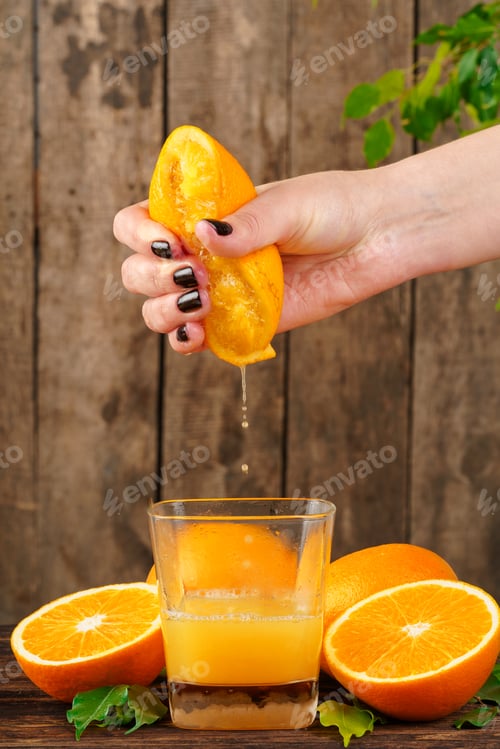 Preview: Woman hand squeezes orange juice close up