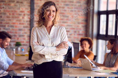 Preview: Portrait Of Smiling Businesswoman Standing In Busy Office