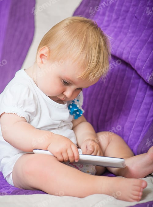 Preview: Toddler Engaged with Mobile Device on Bed