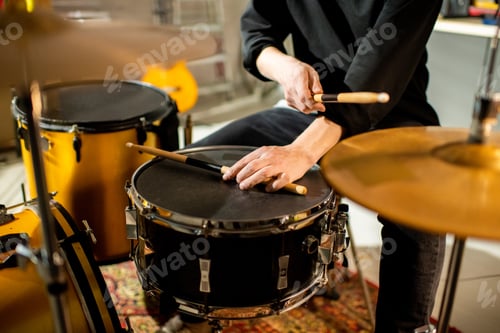 Preview: Hand of young musician putting drumstick on black drum during rehearsal