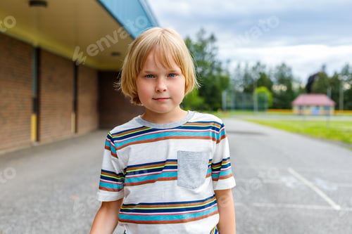 Preview: Portrait of little smiling boy walking to school. Child at schoolyard.