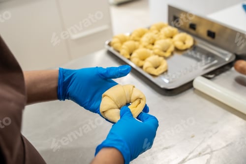 Preview: Baker hands shaping croissant dough on professional kitchen counter