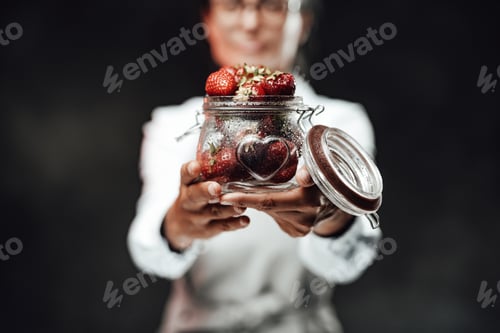 Preview: Close Up view on a wet glass with ripe strawberry. Chef holds a glass with fresh red juicy berries