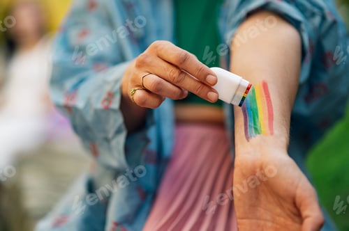 Preview: Woman painting rainbow on arm with cosmetic product