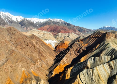 Preview: Multicolored mountains and a valley with snowcapped peaks in distance