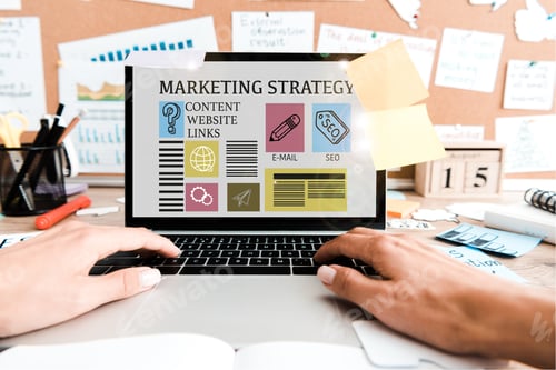 Visualização: visão recortada de mulher usando laptop com letras de estratégia de marketing na tela perto de notas adesivas