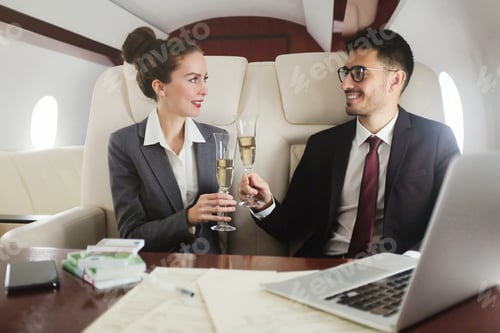 Preview: Business team travelling in private jet, dressed in suits drinking champagne to celebrate success