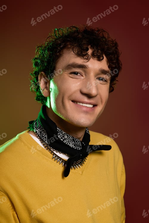 Preview: Stylish man smiles warmly against a vibrant backdrop in a creative, artistic setting