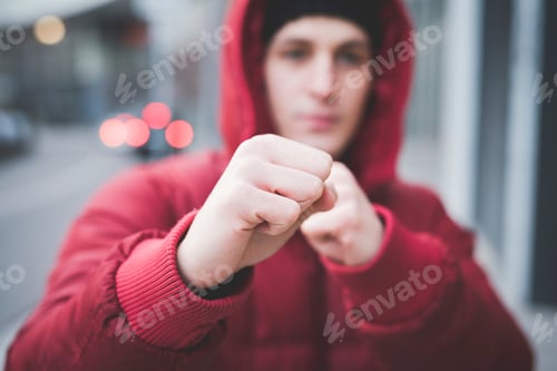 Preview: Close up of young mans posing with clenched fists on city street