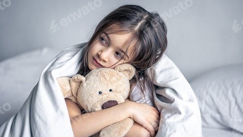 Preview: Little cute girl in bed with a teddy bear early in the morning.