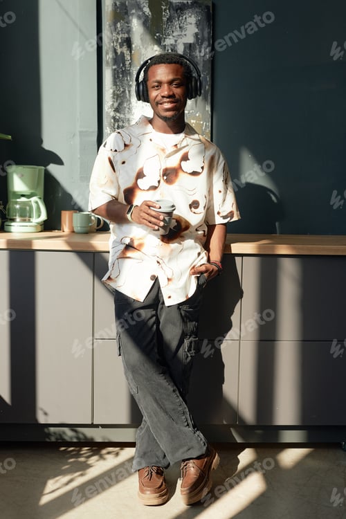 Preview: Smiling Black Man Wearing Headphones and Standing by Coffee Station