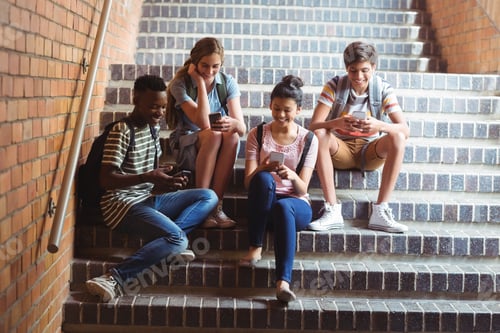 Preview: Classmates sitting on staircase and using mobile phone