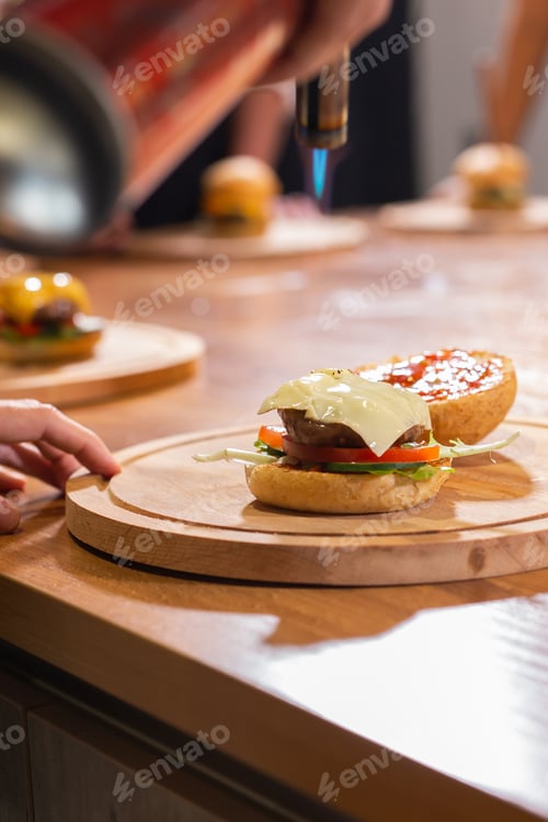 Preview: Preparing delicious burgers. Chef cooking meat burgers with beef, cheese and vegetables. Close-up