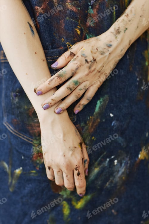 Preview: Close-up of hands of young female painter in denim apron