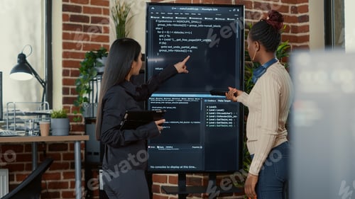Preview: Team of programmers analyzing code on wall screen tv looking for bugs and errors