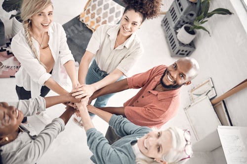 Preview: Group of five cheerful diverse businesspeople piling their hands together in an office at work. Hap