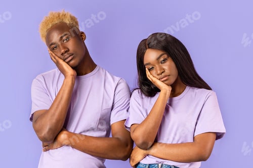 Preview: Bored African American couple with dull facial expressions on color background