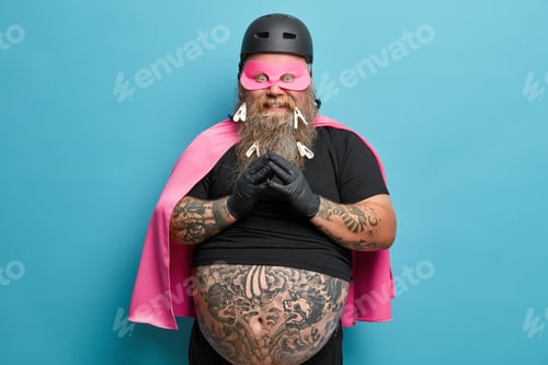 Preview: Horizontal shot of optimistic bearded man keeps hands pressed together dressed in helmet mask and ca