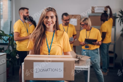 Preview: Portrait of a volunteer holding cardboard box with his colleagues in the background