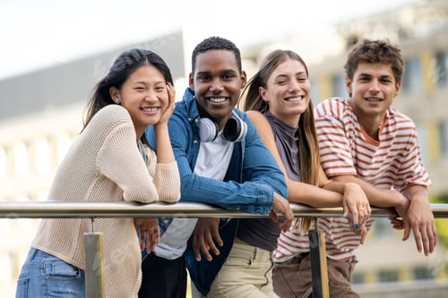 Preview: Beautiful young men and women smiling and looking at camera leaning on a balcony. Diverse group of