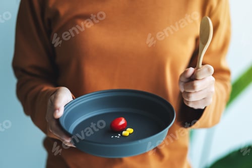 Preview: Closeup image of a woman holding a plate of small amount of food for diet concept