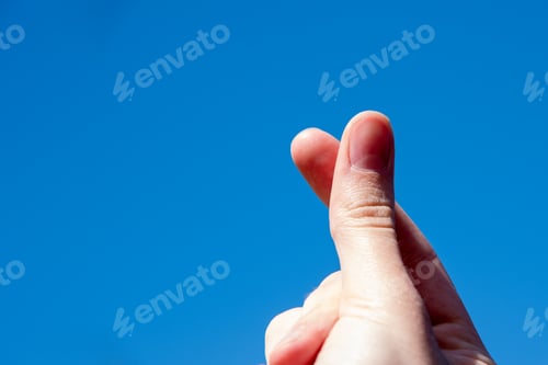 Preview: love gesture on one side against blue sky, friendship sign concept