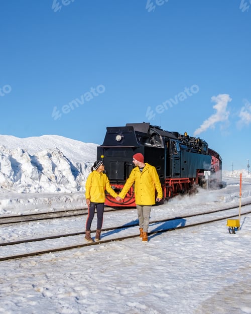 Preview: couple of men and women watching the steam train during winter in the snow in the Harz Germany