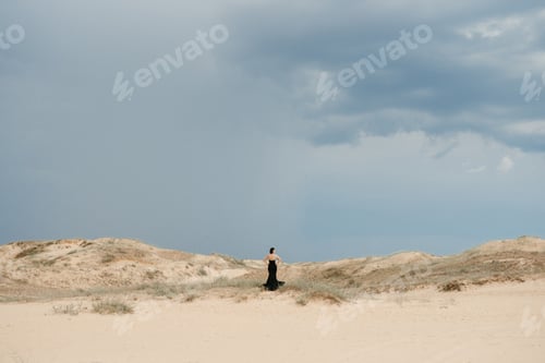 Preview: girl in a black long dress in a sandy desert