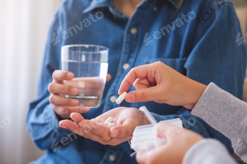 Preview: Closeup image of a woman holding and giving pills to her friend