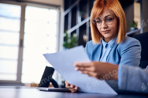 Preview: Focus on the ginger woman, reading one document, and having a meeting with a colleague.