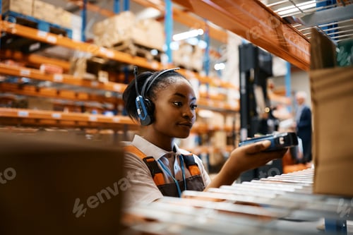Preview: Young black woman scanning packages while working at industrial storage compartment.