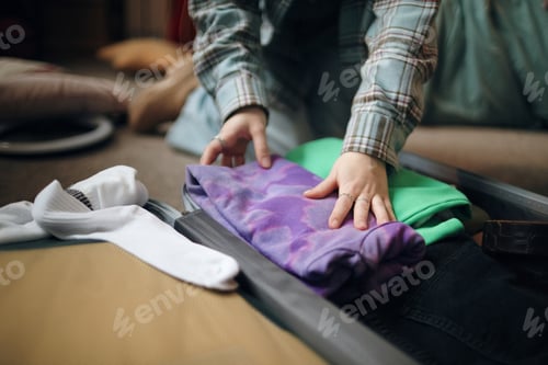 Preview: Young Caucasian Woman Packing Clothes into Suitcase While Preparing for Trip