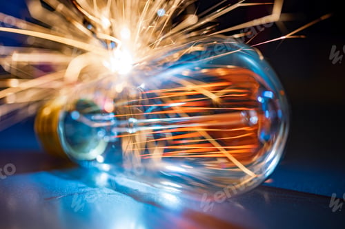 Preview: The incandescent lamp does not shine brightly and sparks fall on the metal surface in a dark room