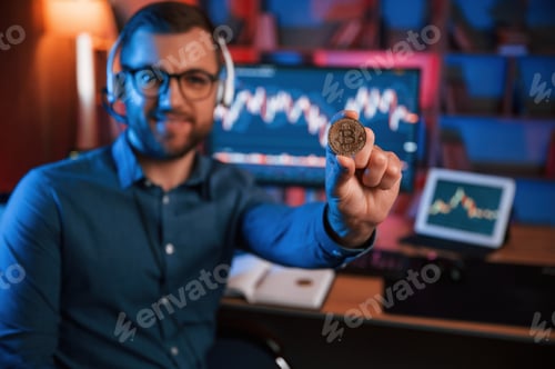 Preview: Holding bitcoin. Stock trader is working by pc indoors. Conception of exchange and money