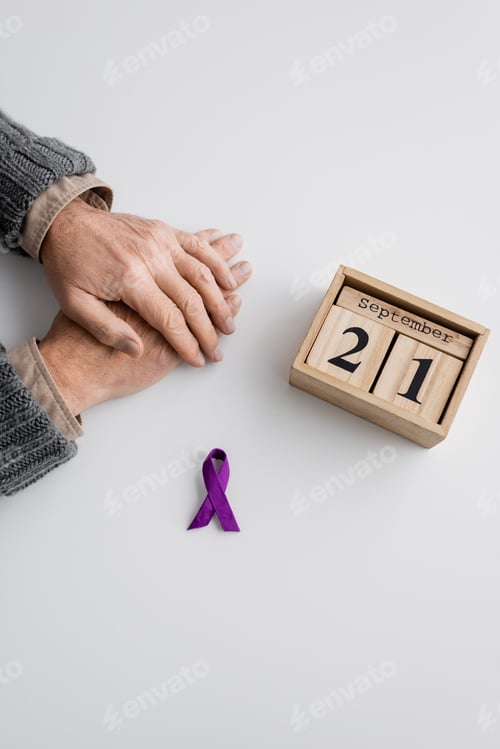 Preview: top view of purple ribbon and wooden calendar with september 21 date near cropped man with