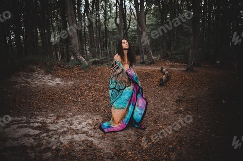 Preview: Caucasian guy with a blanket in forest and closed eyes in Denmark