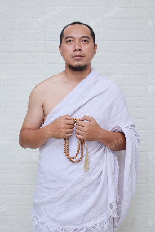 Preview: Asian muslim man in ihram holding rosary or tasbeeh