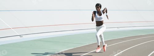 Preview: Beautiful young African woman in sports clothing running on track outdoors