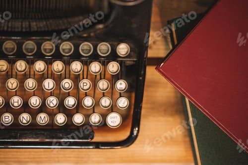 Preview: Old and vintage type writer machine and piles of books on wooden table - in vintage tone.