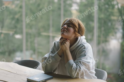 Preview: A Woman is praying near the panoramic window against the background of the forest