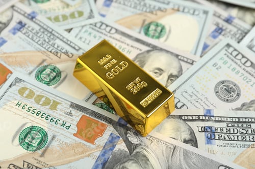 Preview: One shiny gold bar on dollar banknotes, closeup