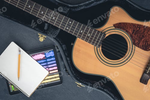 Preview: Acoustic guitar and digital tablet with a music application, top view.