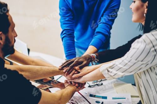 Preview: Diverse group of colleagues stacking hands together in office
