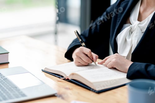 Preview: Close-up of businesswoman holding a pen working by taking note at office.