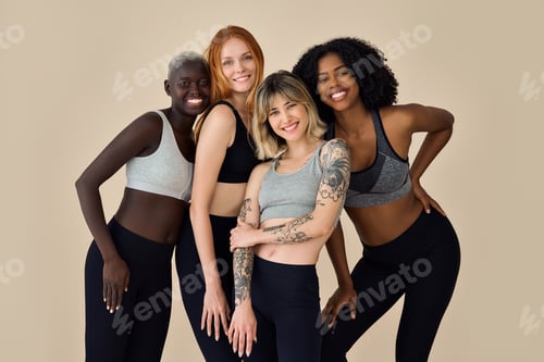 Preview: Happy multicultural models wearing sportswear standing at beige background.