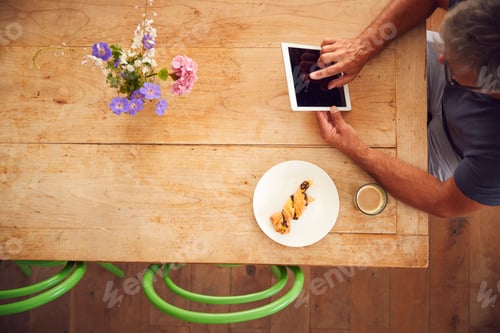 Preview: Overhead View Of Mature Man Working On Digital Tablet In Coffee Shop