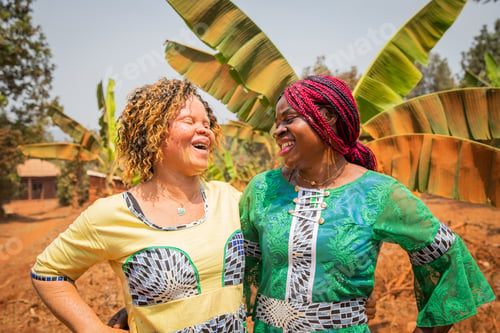 Preview: Two African friends look at each other and laugh, an albino girl with her black friend.