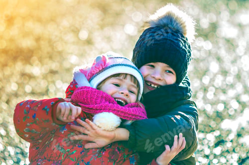 Preview: Two happy children boy and girl playing outdoors in sunny winter day