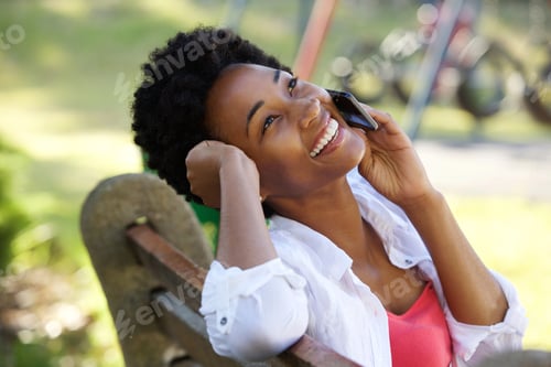 Preview: Relaxed young african woman talking on mobile phone